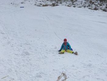 Low angle view of girl sitting on ski slope