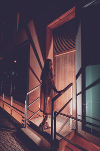 Young woman standing on staircase of building at night