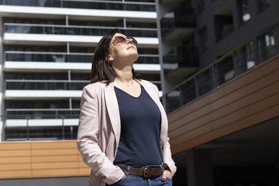 Happy mature 40 yo woman enjoys view of new apartment campus, complex in daytime. female brunette