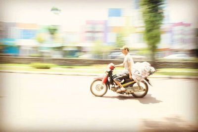 Blurred motion of man riding motorcycle on road