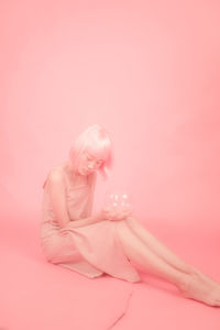 Young woman holding pink flower over white background