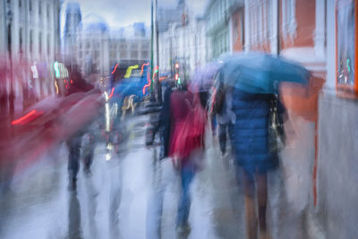 Blurred motion of people walking on city street during rainy season