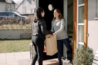 Female customer receiving package from delivery woman