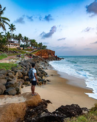 Rear view of woman walking on beach against sky