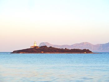 Lighthouse by sea against sky