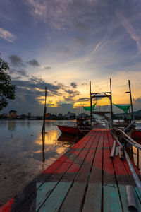 Boats moored at harbor against sky during sunset