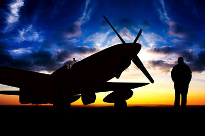 Silhouette man standing by airplane on field against sky during sunset