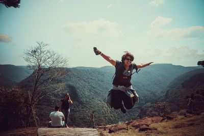 Woman with arms raised against sky