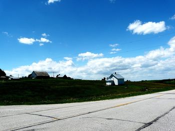 Houses on field by road against sky