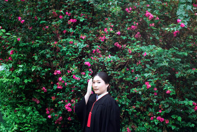 Portrait of beautiful woman standing by flowering plants