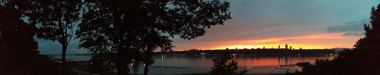 Silhouette trees by lake against sky during sunset