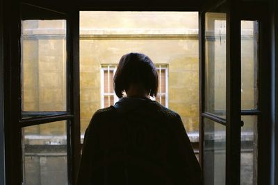 Rear view of man looking through window