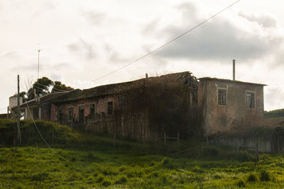 Exterior of old building by field against sky