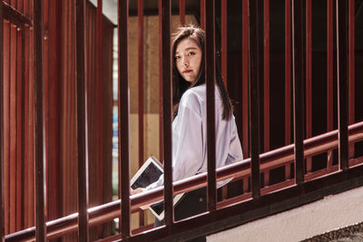 Portrait of woman standing against railing