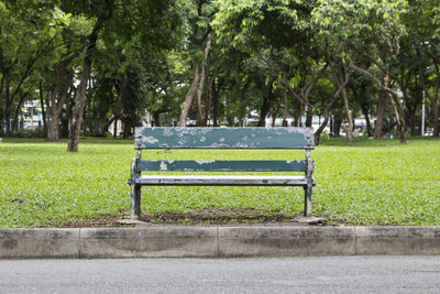 Empty green bench at side of pathway in lumphini park, bangkok thailand