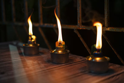 Close-up of lit tea light candles on table in temple