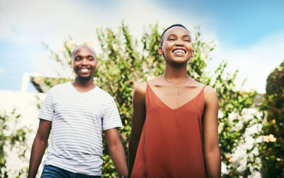 Portrait of smiling young woman standing against trees