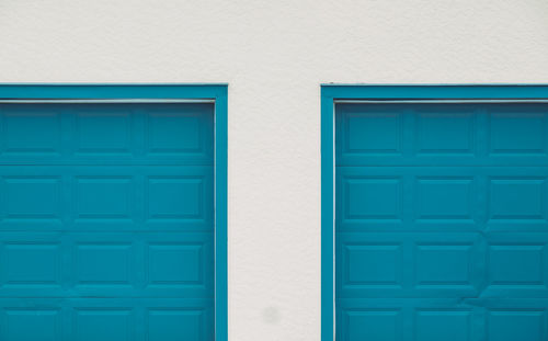 Turquoise wooden doors on white wall