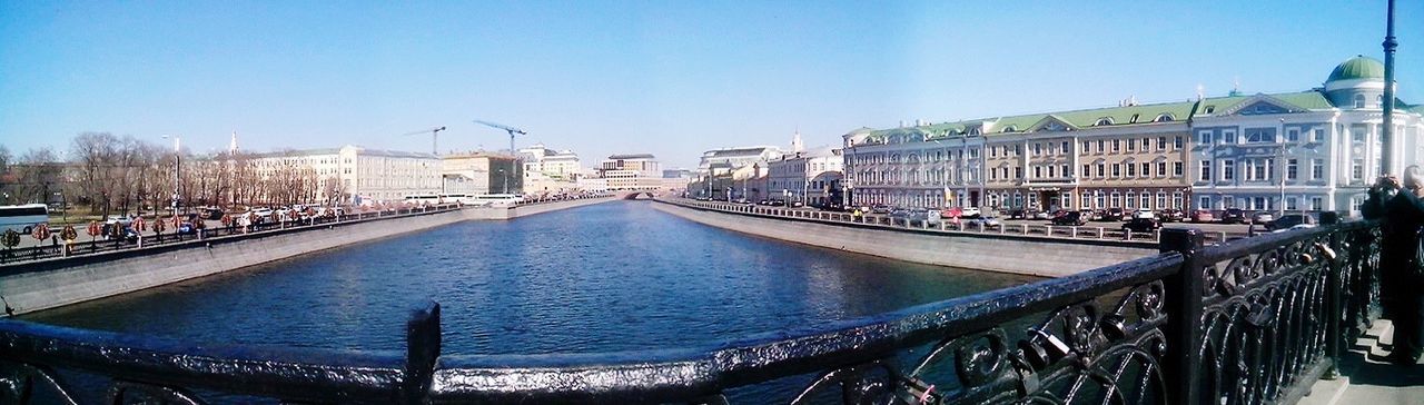 architecture, building exterior, built structure, clear sky, water, canal, city, transportation, blue, copy space, residential structure, residential building, mode of transport, incidental people, railing, river, nautical vessel, travel destinations, sunlight, city life