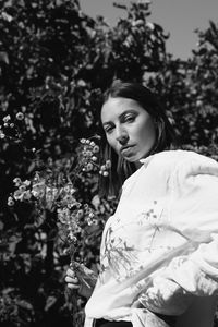 Portrait of young woman standing against plants