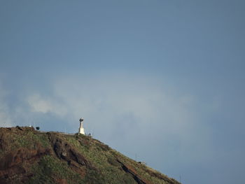 Man standing on rock against sky