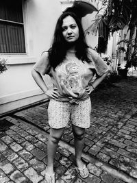 Portrait of young woman standing on footpath