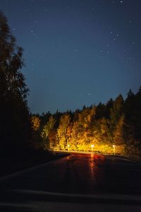 Road amidst trees against sky at night