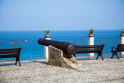 Deck chairs on beach against clear blue sky