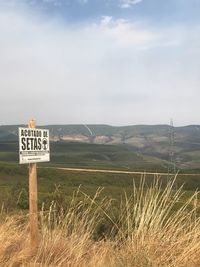 Information sign on field against sky