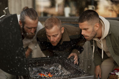 Male friends blowing on barbecue