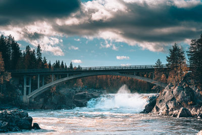 Arch bridge over river against sky