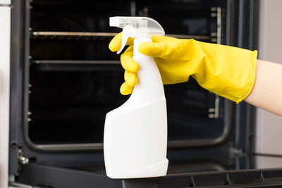 The cleaner holds a mockup of an oven detergent spray bottle 