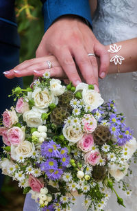 Close-up of hand holding bouquet of red roses