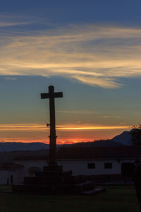 Silhouette cross against sky during sunset