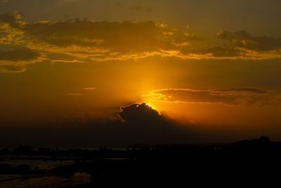 Silhouette landscape against dramatic sky during sunset