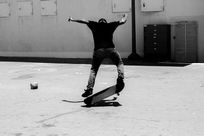 Rear view of man skateboarding at playground during sunny day