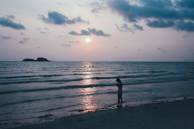 Silhouette man on beach against sky during sunset