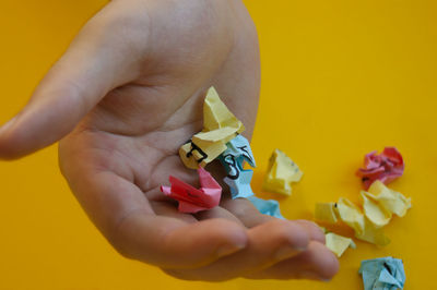 Cropped hand of woman holding toy against yellow background