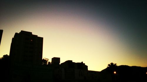 Silhouette of buildings against sky at sunset