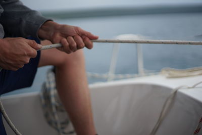 Midsection of man holding rope on boat