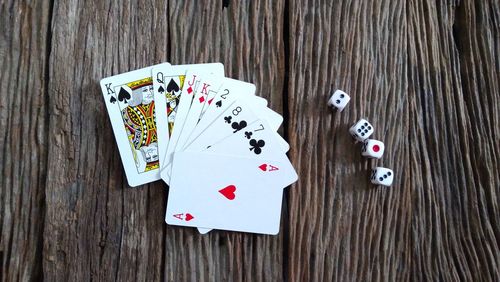 Directly above shot of playing cards with dices on wooden table