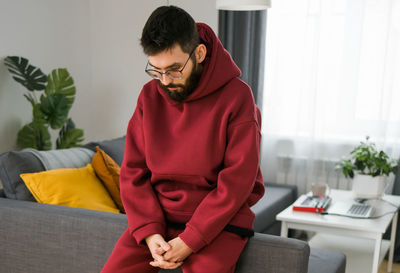 Side view of man using laptop while sitting on sofa at home