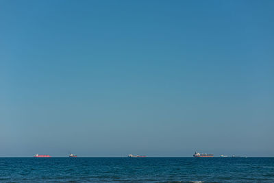 Sailboat sailing in sea against clear blue sky