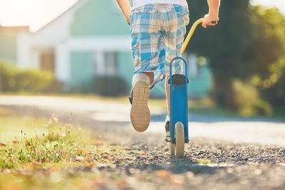 Low section of boy playing with push scooter