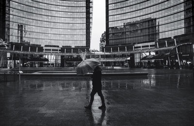 Rear view of man standing on wet glass in city