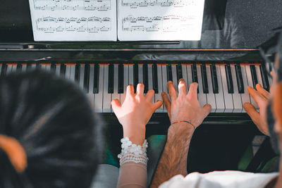 High angle view of father with daughter playing piano at home