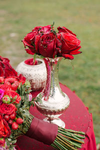 Festive wedding table setting, red roses in a silver vase