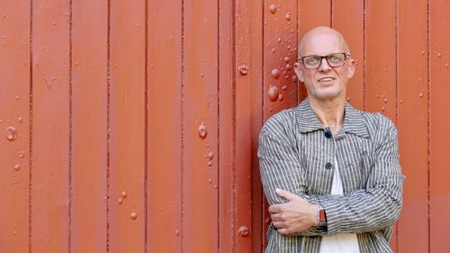 Portrait of smiling young man standing against wall