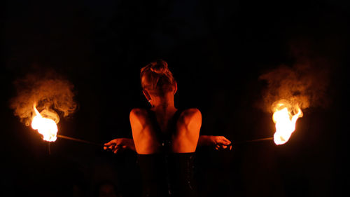 Rear view of woman doing fire stunt night