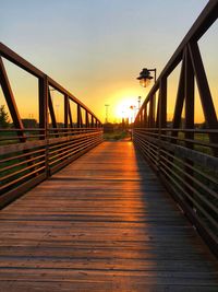 Bridge over footbridge against sky during sunset